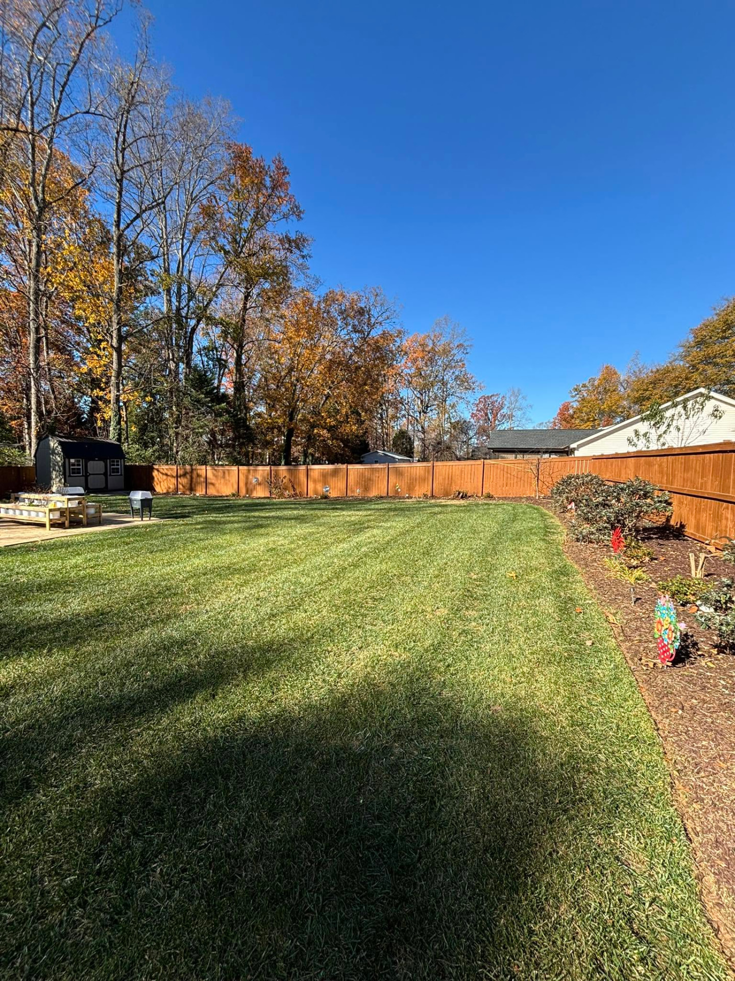 A freshly mowed, striped backyard lawn with clean mulch beds at an Upstate South Carolina home maintained by Kleros Property Care